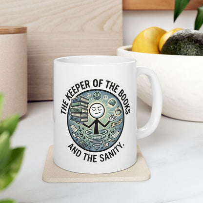White mug with a design and text on a coaster, placed on a surface with a plant and container in the background.