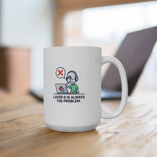 White mug with 'layer 8 is always the problem' logo on a wooden surface